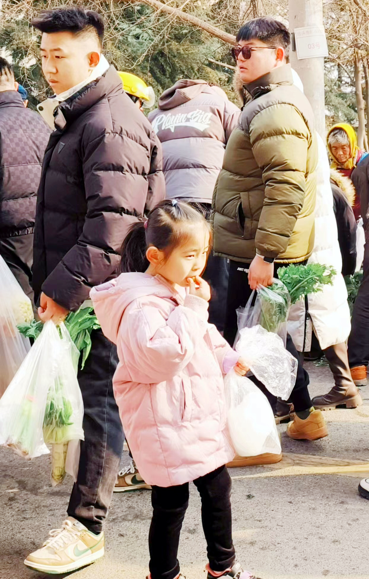 在大集上，一个小女孩趁着热乎吃糖炒栗子。